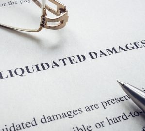 Documents about Liquidated damages with pen and glasses.